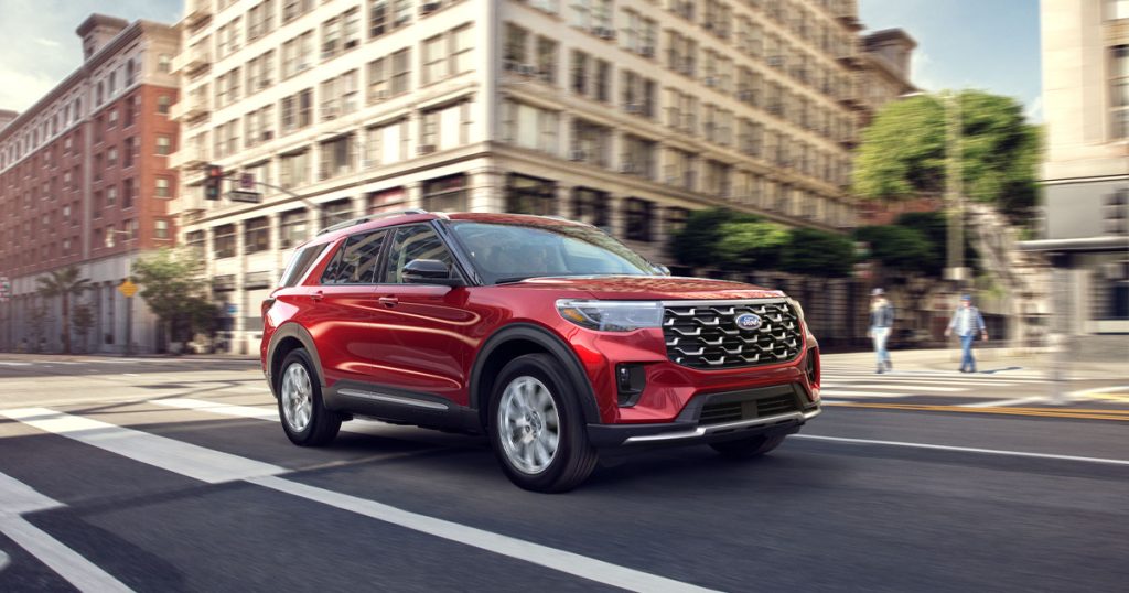 Rapid Red 2025 Ford Explorer driving down a city street.